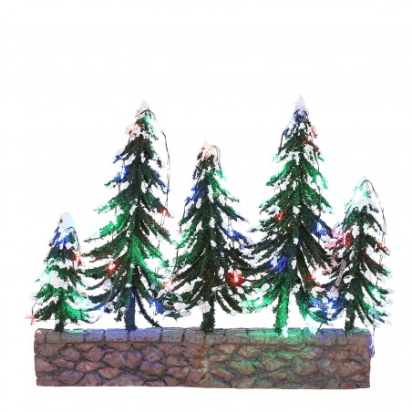 Snowy trees on stone wall with multicolour light battery ope